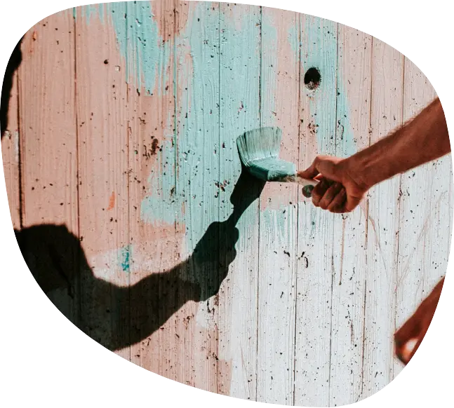 atelier-creatif-peinture-benevoles Main peignant un mur en bois, lors d’un atelier créatif ou d’une action participative avec Passerelle