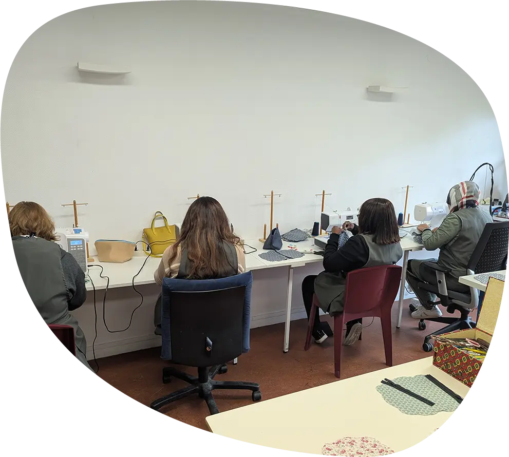 Participants installés aux machines à coudre lors d’un atelier collectif Passerelle